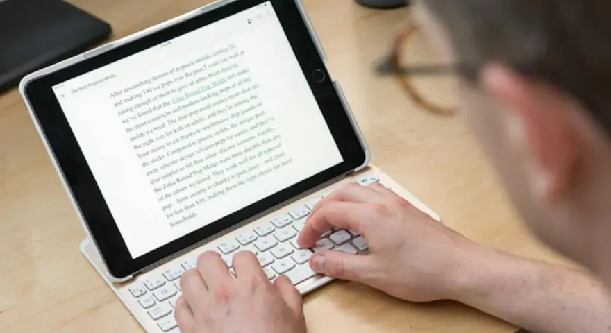 Person skriver på ett iPad-tangentbord. En text om "Zoku Round Pop Molds" visas på skärmen, vilket tyder på ett iPad-tangentbordstest.