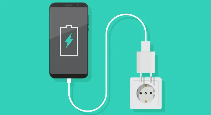 En smartphone med lågt batteri laddas via ett vägguttag.