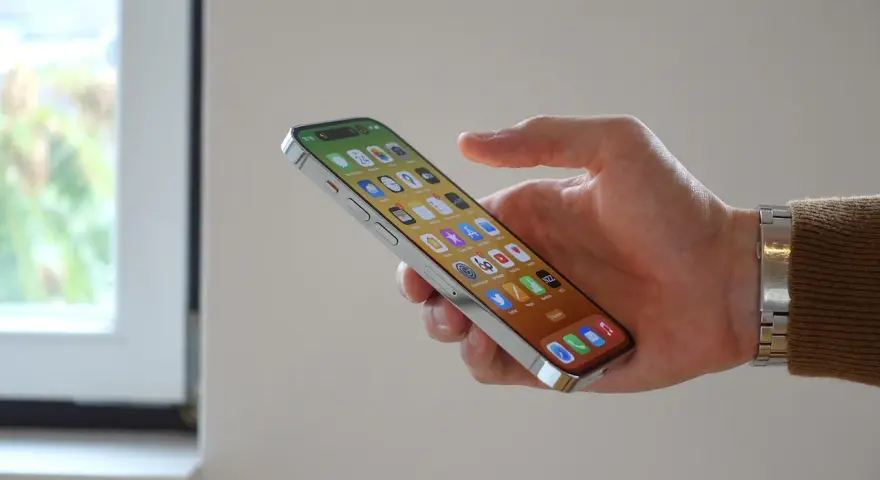 En hand håller en iPhone 12 med många appar. Bra iphone 12 batteritid gör att du kan använda den hela dagen.