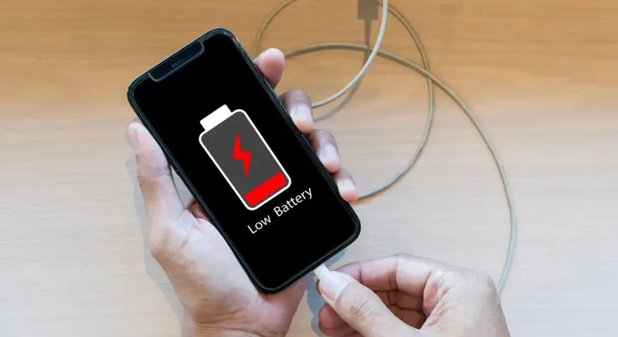 En person laddar sin mobiltelefon med lågt batteri. Viktigt att spara bilder från mobilen innan batteriet tar slut!