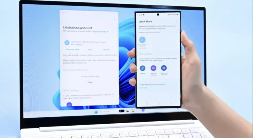 En hand håller en Samsung-telefon framför en laptop. Laptopen visar ett fönster för filöverföring, vilket underlättar att byta från iPhone till Samsung.