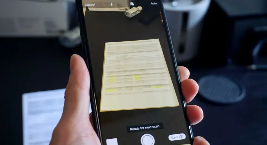 En hand håller en iPhone för att scanna ett dokument. Skärmen visar en förhandsgranskning av det skannade dokumentet och alternativ för att avbryta eller spara.