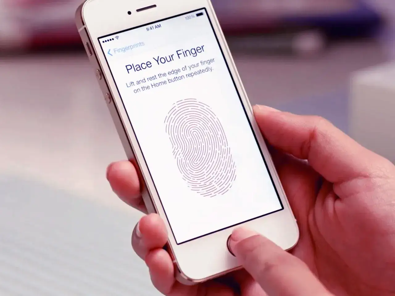 En hand håller en iPhone som visar instruktioner för att registrera fingeravtryck med touch ID.