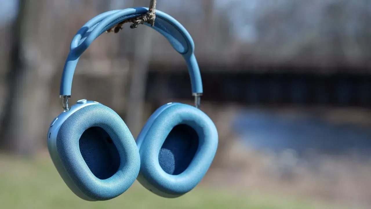 Blå AirPods Pro Max 2 hänger från en gren utomhus, redo för en ljudupplevelse i naturen.