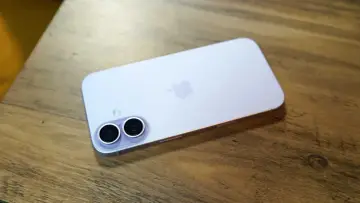 En ljuslila iPhone med dubbla kameror ligger på ett träbord. Vilken iPhone har jag?